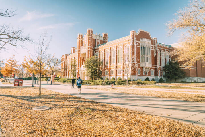 A scenic view of a historic university building surrounded by autumn foliage, reflecting academic architecture.