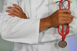 medical website design featured image - toros of a doctor with arms crossed holding a red stethoscope
